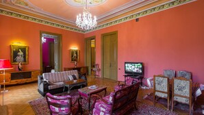 A living room with a sofa, chairs, a television, and a chandelier.
