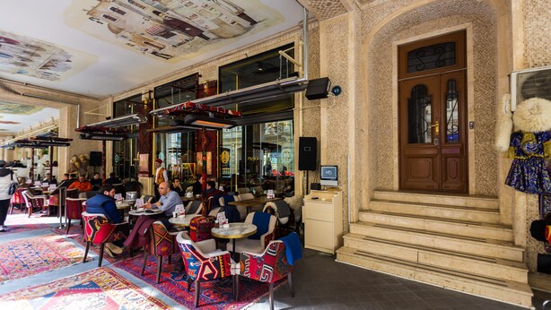 A restaurant with tables and chairs, a large window, and a door with a sign above it.