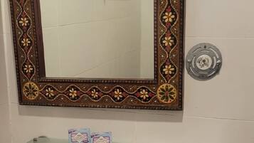 A bathroom with a white sink, a decorative mirror with a floral frame, and patterned tiles on the walls.