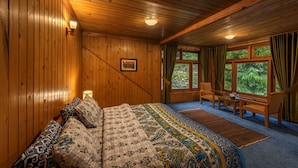 A wooden-paneled bedroom with a bed, a desk, and a chair. - Pine Park Edge Resort Khanian (Balakot)