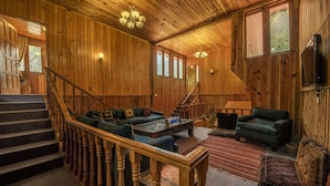 A spacious wooden interior with a staircase, multiple seating areas, and a television. - Pine Park Edge Resort Khanian (Balakot)
