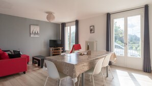 A modern living room with a dining table, red sofa, and a TV. - La Saline - Wifi - Parking - Jardin (Villeneuve-en-Retz)