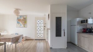 A modern kitchen with a microwave, a refrigerator, and a sink. There is a dining area with a table and chairs. - La Saline - Wifi - Parking - Jardin (Villeneuve-en-Retz)