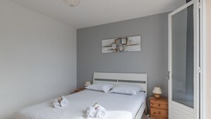 A bedroom with a bed, a nightstand, a lamp, and a door. - La Saline - Wifi - Parking - Jardin (Villeneuve-en-Retz)