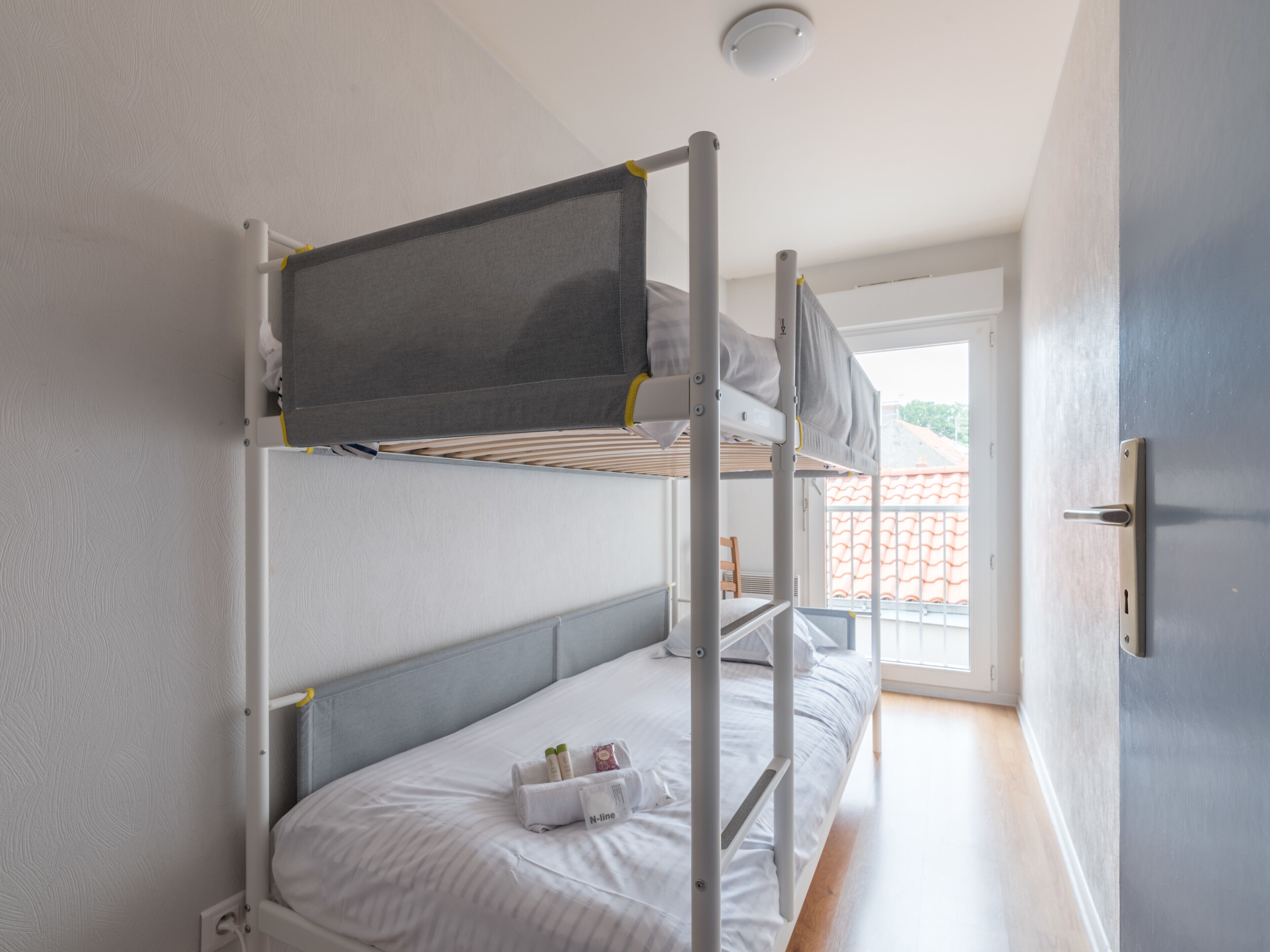 A bunk bed room with a window and a door.