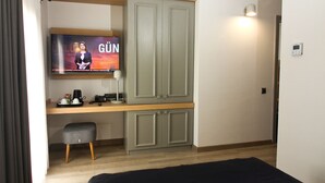 Habitación de hotel con una cama, un escritorio con televisor y un armario.
