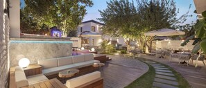 An outdoor seating area with a curved wooden deck, cushioned seating, and a small fountain. - Mellow Blue Hotel (Seferihisar)