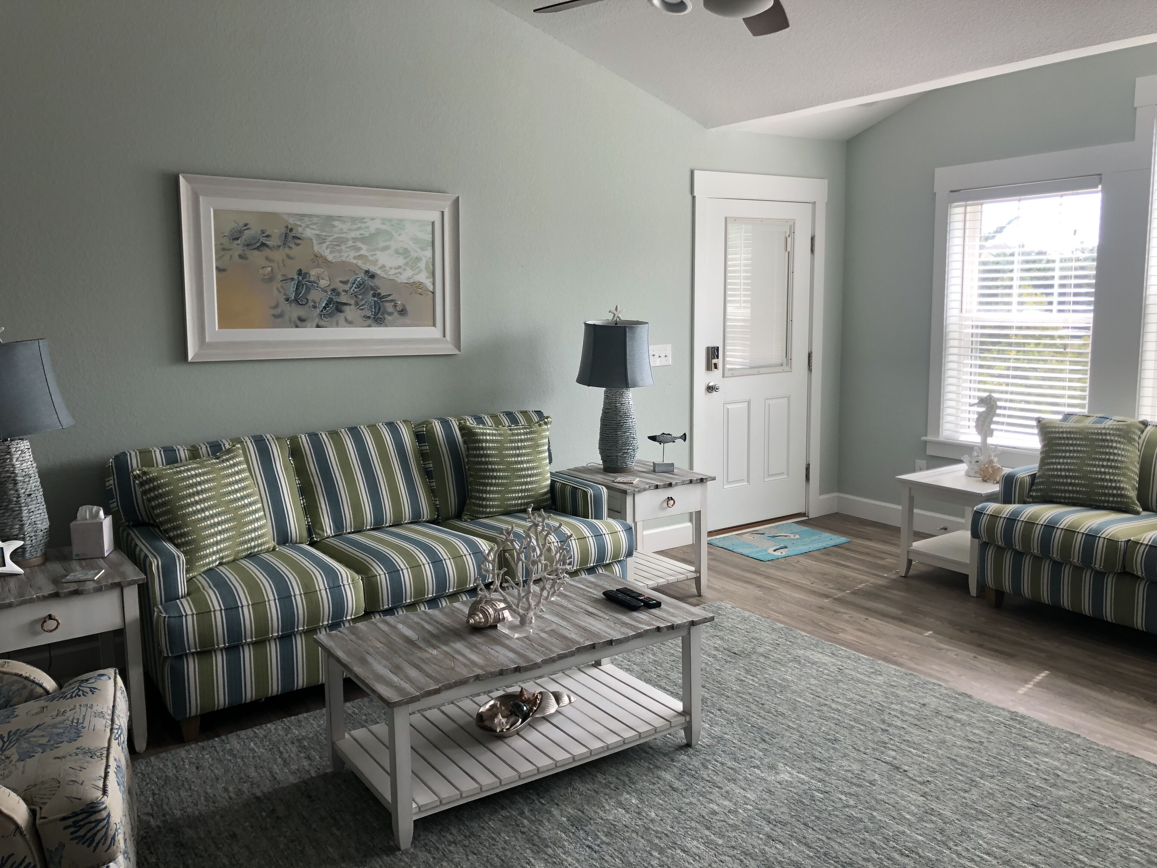 A living room with striped couches, a coffee table, a lamp, and a framed picture on the wall.