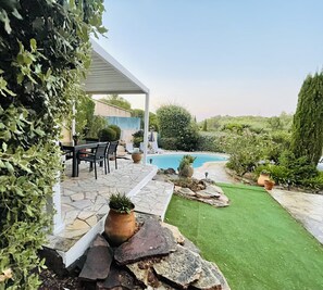 A covered patio area with a pool, stone flooring, and a lawn. - Private villa with pool (Saint-Raphaël)