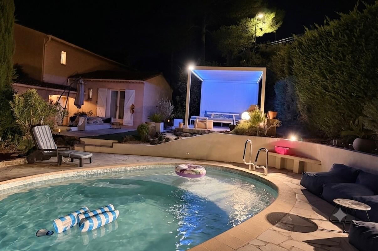 A swimming pool with lounge chairs and a hot tub area, surrounded by a landscaped garden.