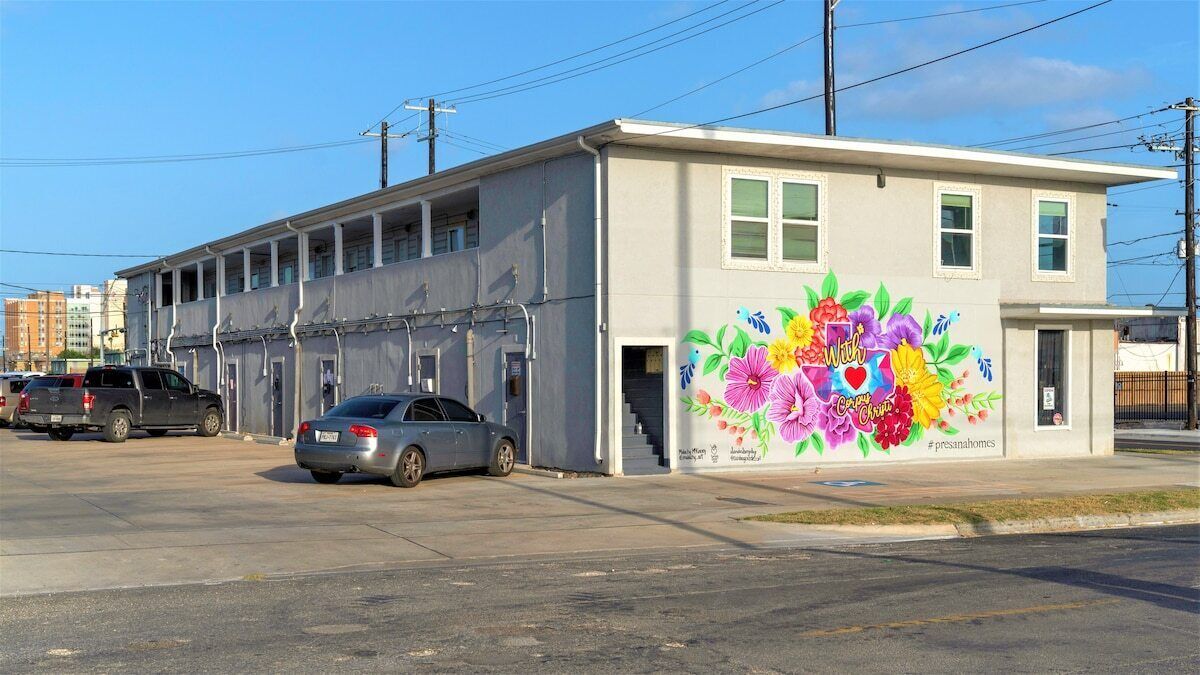 A building with a colorful mural on the side, a parking lot, and a clear sky.