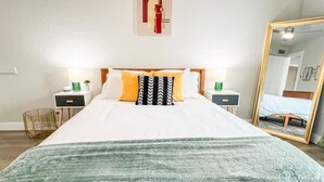 A neatly arranged hotel room with a large bed, two bedside tables, a mirror, and a wall-mounted artwork.