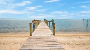 A wooden pier extending into calm waters with a clear sky above. - Sea Glass Beach House!  Large sand beach, dock and hot tub! Pets welcome!  (Hague)
