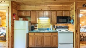 Une cuisine de taille réduite, dotée de meubles en bois, d’un réfrigérateur, d’un four à micro-ondes et d’une cuisinière.