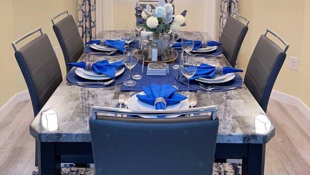 Ein Esszimmer mit Marmortisch, blauen Servietten und einem Kronleuchter.