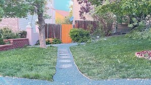 Ein Weg führt zu einem Haus mit Holzzaun und Backsteinmauer.