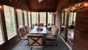 A log cabin with a dining area featuring a table and chairs, large windows, and a ceiling fan. - Pocono Chalet Cabin Sauna Game Room Fire Pit Pools (Bushkill)