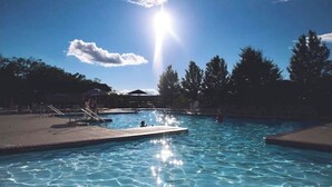 A swimming pool with clear blue water, surrounded by trees and a sunny sky. - Pocono Chalet Cabin Sauna Game Room Fire Pit Pools (Bushkill)