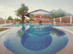 A swimming pool with a mosaic design, surrounded by a fence and trees. - COTTAGES Resort - Ong Lang Beach (Phu Quoc)