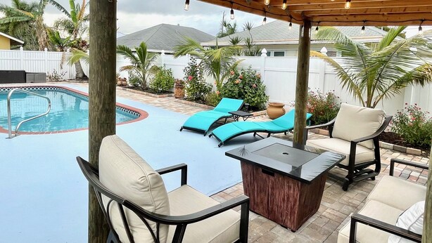 Un espace extérieur abrité comprenant une piscine, des chaises longues et une table.