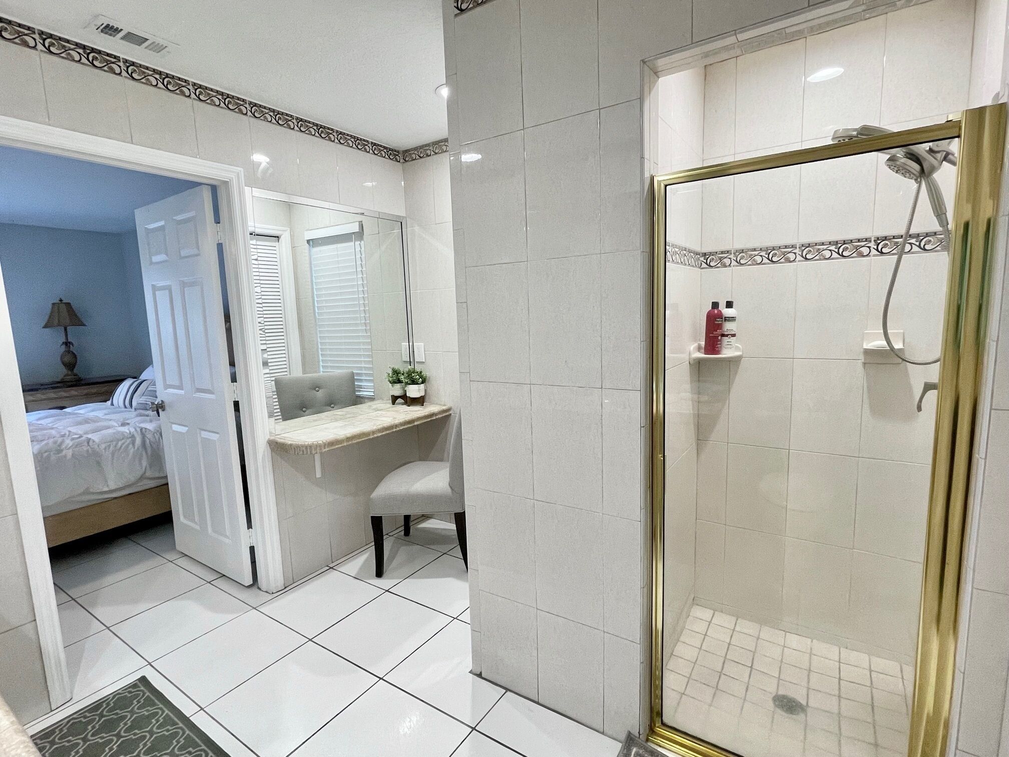 Une salle de bain moderne avec douche, un meuble-lavabo et un lit dans la pièce adjacente.