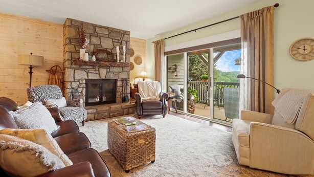 Una sala de estar acogedora con chimenea de piedra, sofás de cuero y vistas al exterior a través de amplios ventanales correderas.