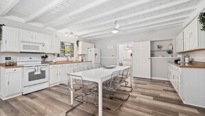 Ett modernt kök med vita skåp, en köksö och en matplats med stolar.