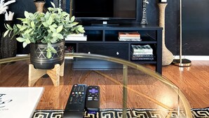 Un salon moderne doté d’un grand téléviseur à écran plat, d’une horloge décorative et d’un lampadaire élégant.