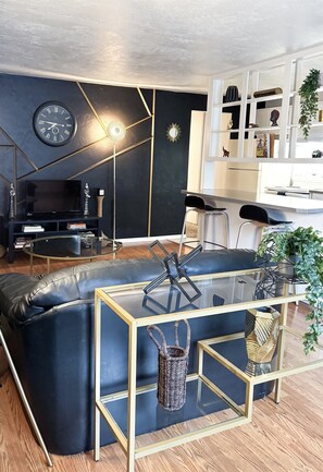 A modern living room with a black sectional sofa, a glass coffee table, and a white bookshelf. - Ebony Escape- gym, sauna, hot tub, seasonal pool (Corvallis)