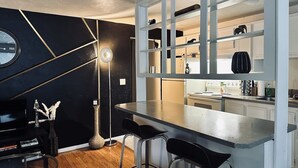 Une cuisine moderne avec un coin bar, des meubles blancs et un mur d’accent noir.