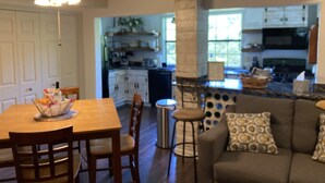 Una cocina amplia con una isla central, mesa de comedor de madera con sillas y un taburete de bar.