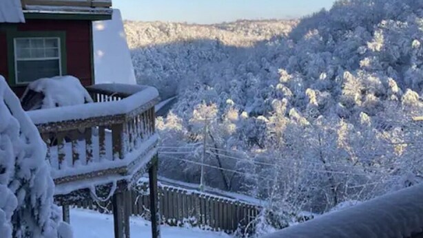 Un paisaje nevado con una casa y una terraza de madera.