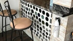 Cocina con encimera de mármol, protector contra salpicaduras estampado y dos taburetes de bar.