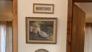 Une pièce avec un cadre de porte en bois, un tableau encadré représentant des oiseaux et une pancarte de bienvenue.