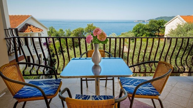 Ein Balkon mit Tisch und Stühlen mit Blick auf die Küste.