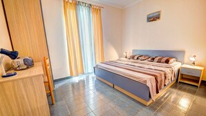Ein Schlafzimmer mit einem Bett, Nachttischen, einem Schreibtisch mit Lampe und einem Fenster mit Vorhängen.