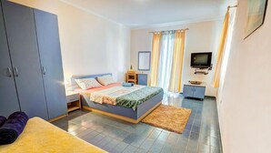 Ein Schlafzimmer mit einem Bett, einem Schreibtisch, einem Fernseher und einem Kleiderschrank.