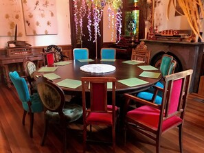 A round dining table with green placemats, surrounded by chairs with red and blue upholstery. - Bywater Wonderland, 2 blocks to the river, close to many good things! (New Orleans)