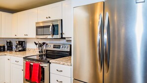 A modern kitchen with white cabinets, a stainless steel refrigerator, a microwave, a coffee maker, and a red towel hanging on the oven handle. - Casa De Azul ~ Fabulous Private Pool Paradise ~ Spacious And Comfy! (Tucson)