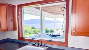 A kitchen with a large window, a sink, and wooden cabinets.