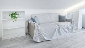 Ein modernes Wohnzimmer mit einem gestreiften Sofa, einer weißen Regaleinrichtung und einer grünen Pflanze.