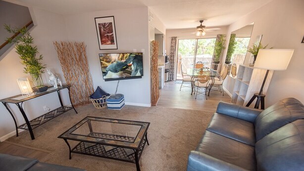 Un salon avec un canapé en cuir, une table basse en verre et un téléviseur fixé au mur.