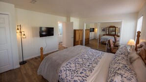 Une chambre à coucher avec un lit, une télévision, une lampe sur pied et un miroir.