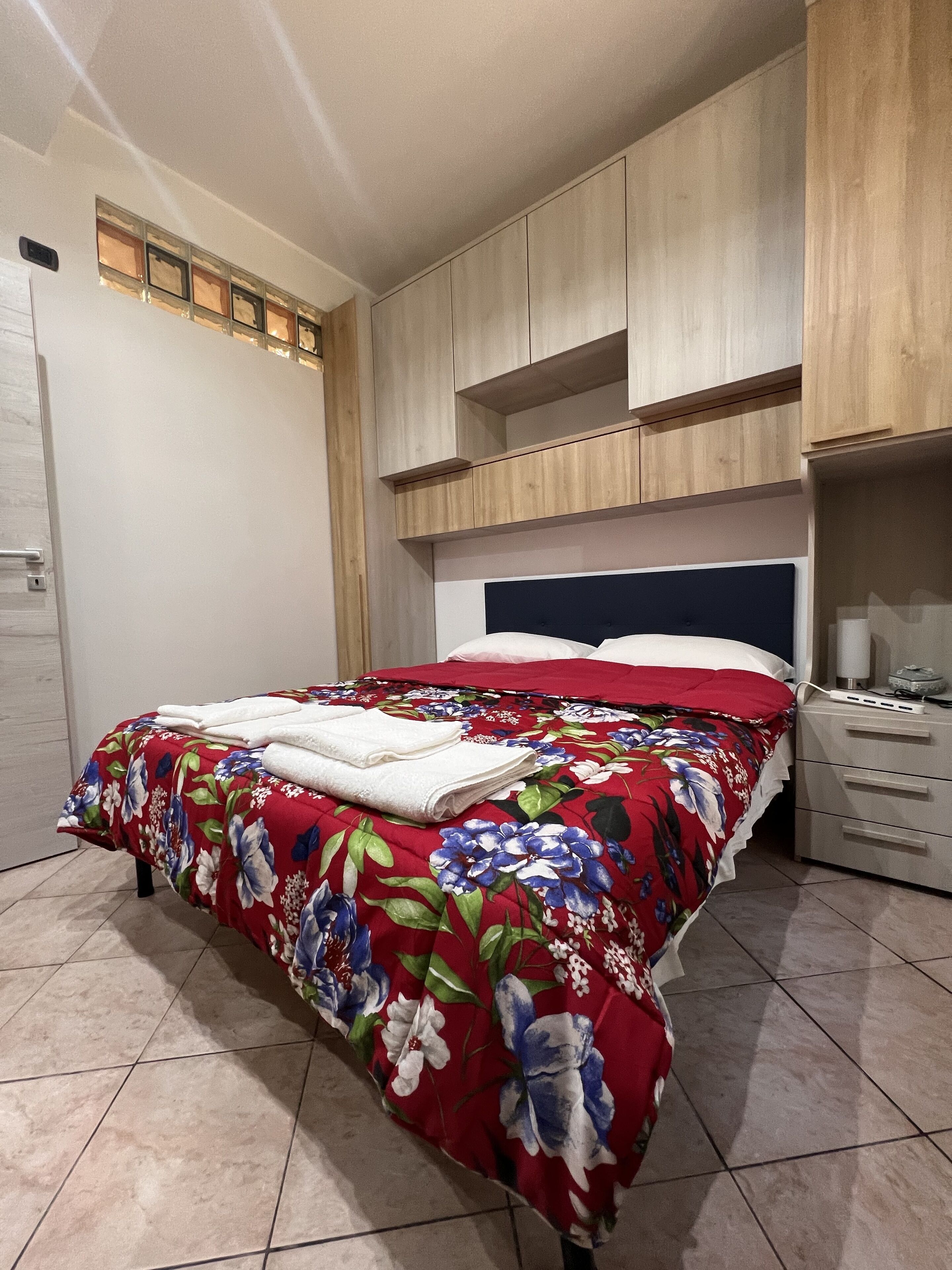 A bedroom with a bed, a nightstand, a dresser, and built-in wooden shelving.