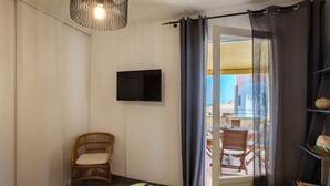 A bedroom with a bed, a television, a chair, and a view of the outside. - Casa Chjara Maria (Vescovato)