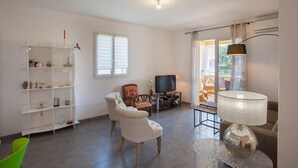 A living room with a white sofa, a TV, a bookshelf, and a lamp. - Casa Chjara Maria (Vescovato)