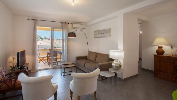 A modern living room with a sofa, chairs, a TV, and a dining area with a table and chairs. - Casa Chjara Maria (Vescovato)