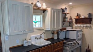Cocina compacta con armarios de madera, un lavamanos, una estufa y una ventana con un diseño de vitral.