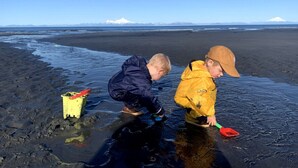 Two children playing on a beach with a clear sky and distant mountains. - Ocean-view Cabin on the Anchor Point Bluff (Anchor Point)