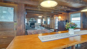 A wooden interior with a large dining table, a map on the wall, and a kitchen area in the background. - Historic Cottage w/ Beautiful Oceanfront View (Marshfield)